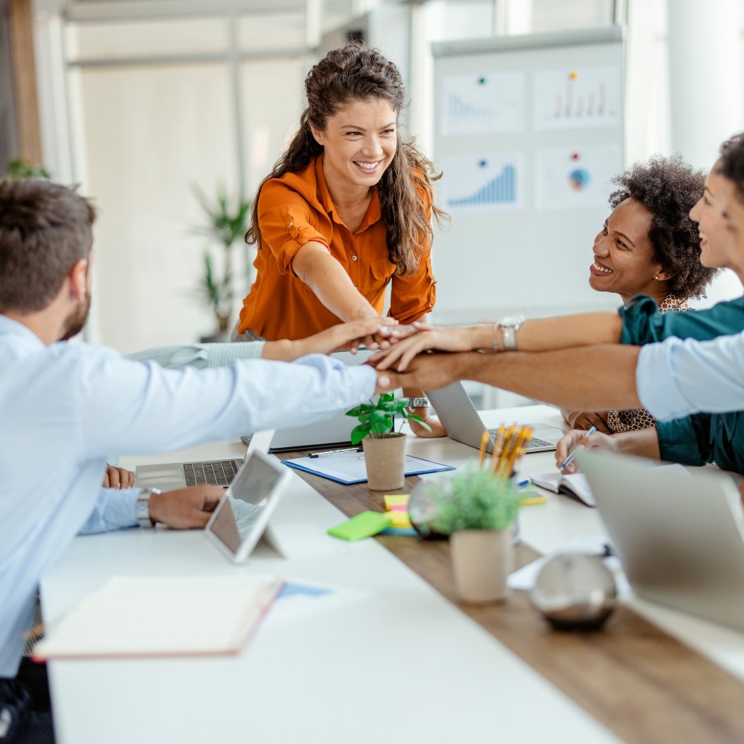 A diverse group of business professionals high-fiving and collaborating, demonstrating teamwork and success in the workplace.